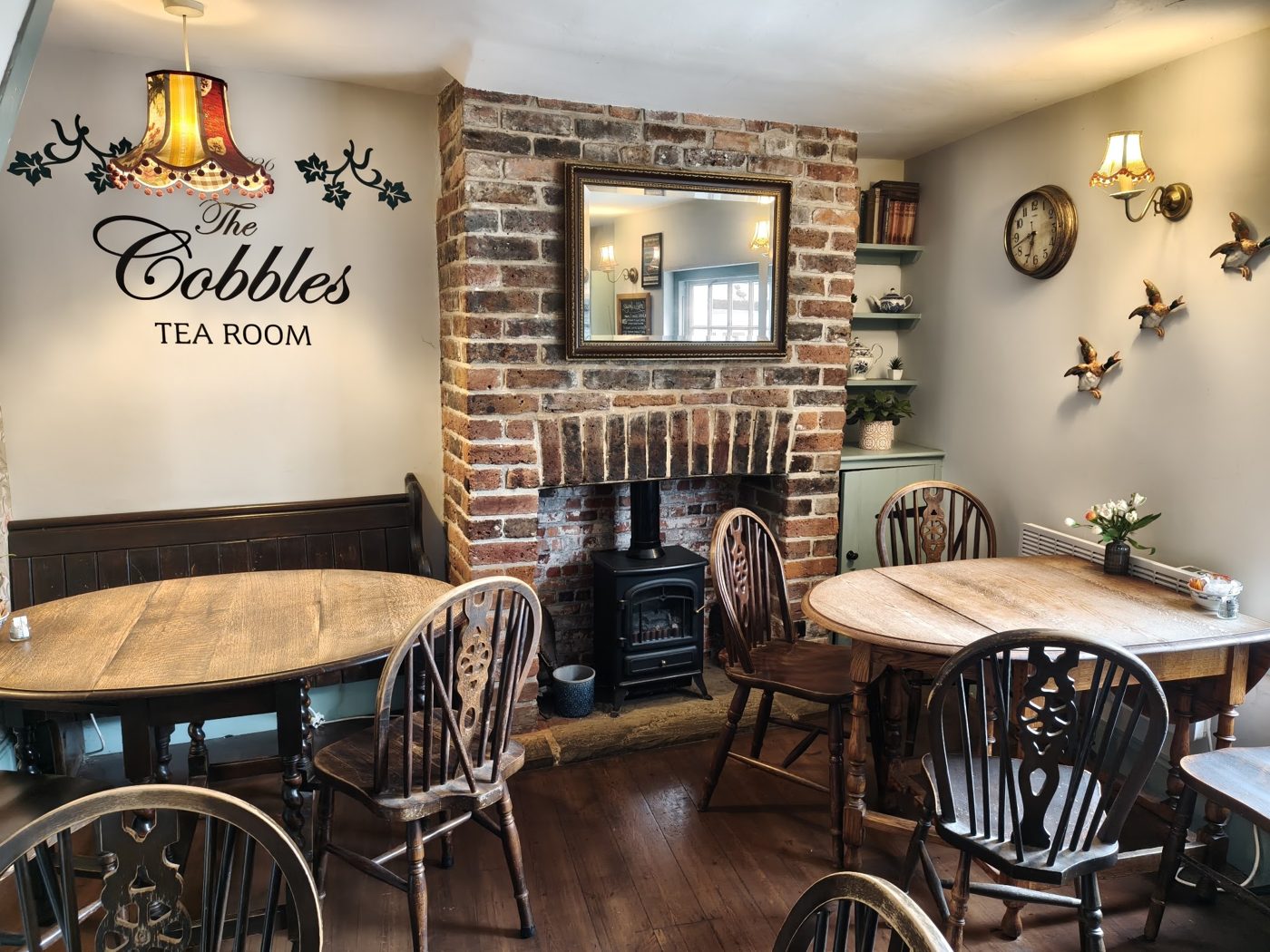 Inside: wooden tables, a brick fireplace and The Cobbles Tea Room sign on the wall